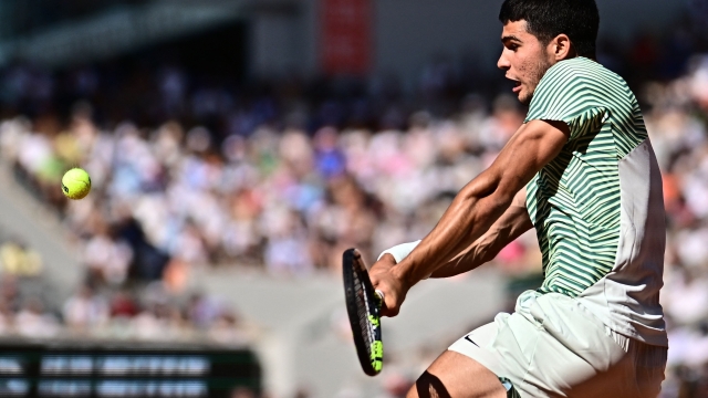 Spain's Carlos Alcaraz Garfia plays a backhand return to Italy's Lorenzo Musetti during their men's singles match on day eight of the Roland-Garros Open tennis tournament at the Court Philippe-Chatrier in Paris on June 4, 2023. (Photo by JULIEN DE ROSA / AFP)