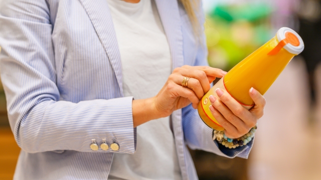 Woman reading ingredients and nutrition information on juice bottle's etiquette
