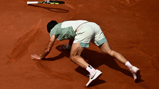 TOPSHOT - Spain's Carlos Alcaraz Garfia falls on the court as he plays against Serbia's Novak Djokovic during their men's singles semi-final match on day thirteen of the Roland-Garros Open tennis tournament at the Court Philippe-Chatrier in Paris on June 9, 2023. (Photo by JULIEN DE ROSA / AFP)
