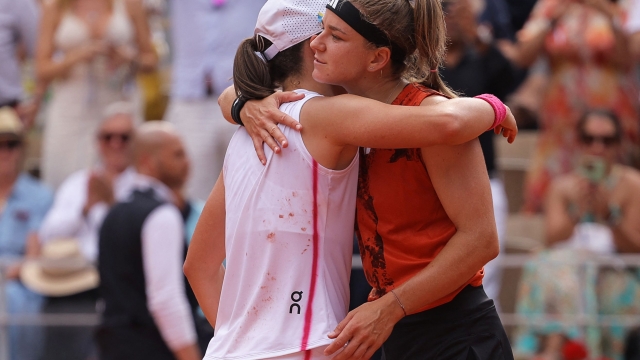 Poland's Iga Swiatek (L) comforts Czech Republic's Karolina Muchova after her victory during their women's singles final match on day fourteen of the Roland-Garros Open tennis tournament at the Court Philippe-Chatrier in Paris on June 10, 2023. (Photo by Thomas SAMSON / AFP)