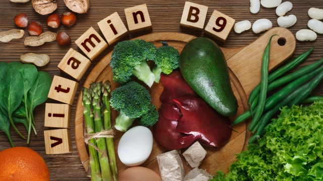 Foods rich in vitamin B9 (folic acid) as liver, asparagus, broccoli, eggs, salad, avocado, yeast, nuts, spinach, orange and beans. Top view