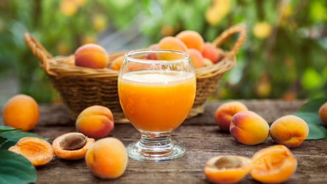 Glass with apricot juice and apricots around glass