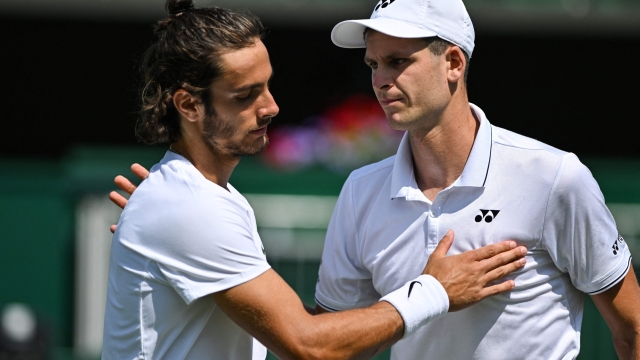 Poland's Hubert Hurkacz (R) hugs Italy's Lorenzo Musetti (L) after winning their men's singles tennis match on the fifth day of the 2023 Wimbledon Championships at The All England Tennis Club in Wimbledon, southwest London, on July 7, 2023. (Photo by Glyn KIRK / AFP) / RESTRICTED TO EDITORIAL USE
