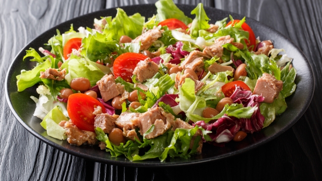 Mediterranean salad with tuna fish, borlotti beans, cherry tomatoes, lettuce close-up on a plate on the table. horizontal
