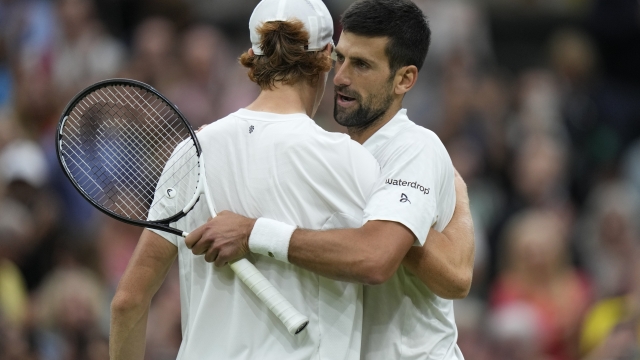 Serbia's Novak Djokovic, right, embraces Italy's Jannik Sinner after winning their men's singles semifinal match on day twelve of the Wimbledon tennis championships in London, Friday, July 14, 2023. (AP Photo/Alastair Grant)