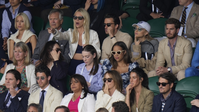 Actor Andrew Garfield, top right, singer Ariana Grande, second top right, actor Daniel Bruehl, bottom left, and singer Nick Jonas, bottom second left, sit in the stands on Centre Court for the final of the men's singles between Spain's Carlos Alcaraz and Serbia's Novak Djokovic on day fourteen of the Wimbledon tennis championships in London, Sunday, July 16, 2023. (AP Photo/Alastair Grant)