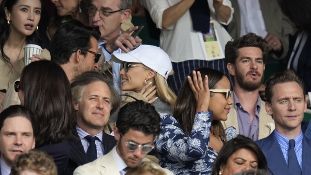 Actor Andrew Garfield, top right, singer Ariana Grande, center, and actor Tom Hiddleston, bottom right, sit in the stands on Centre Court for the final of the men's singles between Spain's Carlos Alcaraz and Serbia's Novak Djokovic on day fourteen of the Wimbledon tennis championships in London, Sunday, July 16, 2023. (AP Photo/Kirsty Wigglesworth)