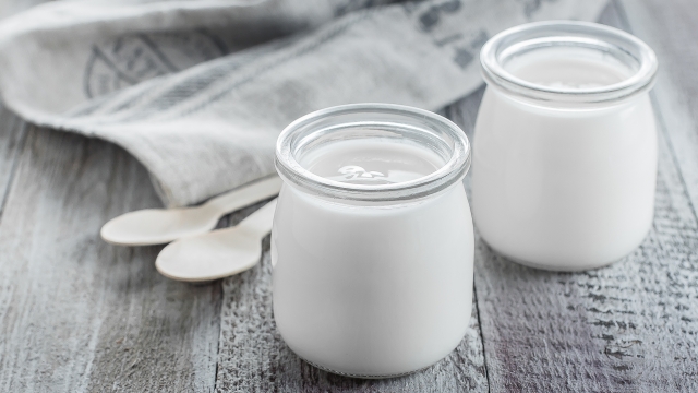 Greek yogurt in a glass jars with wooden spoons on wooden background. Healhty Breakfast Food. Copy space