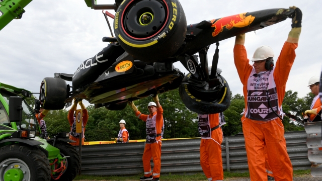 Track marshals remove the car of Red Bull Racing's Mexican driver Sergio Perez (not in picture) from the racetrack after he crashed into the barriers during the first practice session at the Hungaroring race track in Mogyorod near Budapest on July 21, 2023, ahead of the Formula One Hungarian Grand Prix. (Photo by Ferenc ISZA / AFP)