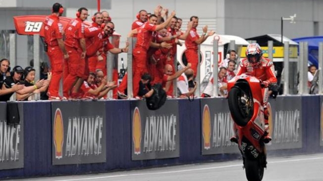 Australian rider Casey Stoner of Ducati wheelies past team members  as he celebrates his race victory of the Malaysian Motocycle Grand Prix at the Sepang racing circuit on October 25, 2009. Meanwhile defending world champion Valentino Rossi claimed his seventh MotoGP title in wet track conditions. AFP PHOTO/ROSLAN RAHMAN