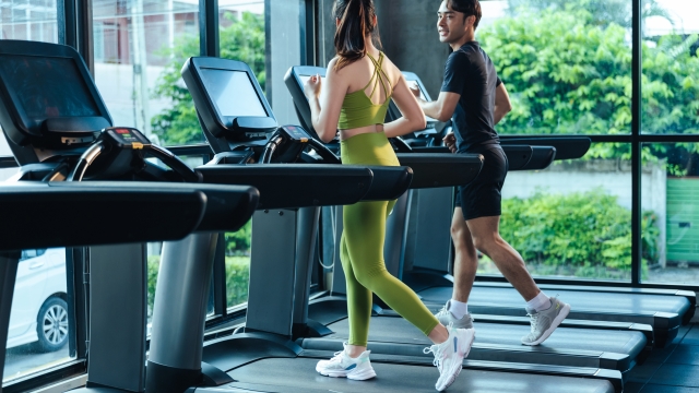 Together Asian man and woman healthy in sportswear cardio exercise jogging on a treadmill in fitness gym. Sport people workout indoor for good health. Healthy lifestyle concept.