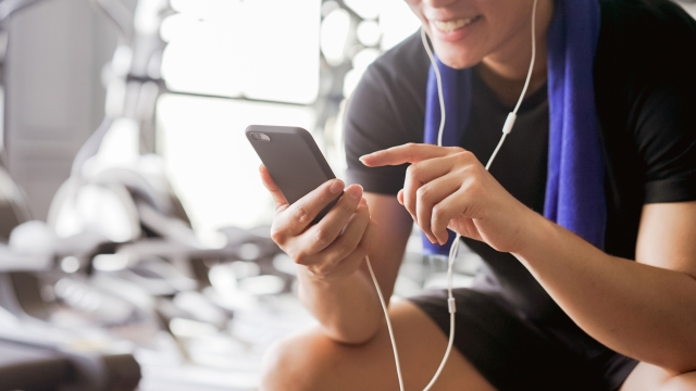close up young asian man holding smartphone and choose list of music player for listening after finish exercise at gym, healthy lifestyle concept