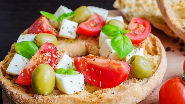 Italian appetizer Friselle. Italian dried bread Friselle on wooden board with tomatoes cherry, basil and olives. Italian food. Healthy vegetarian food. Selective focus.
