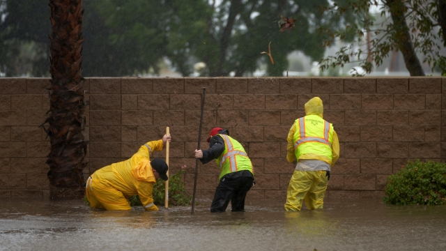 epa10811209 Public works employees try to unclog a drain due to flooding as Tropical Storm Hilary arrives in Rancho Mirage, California, USA, 20 August 2023. Southern California is under a tropical storm warning for the first time in history as Hilary makes landfall. The last time a tropical storm made landfall in Southern California was 15 September 1939, according to the National Weather Service.  EPA/ALLISON DINNER