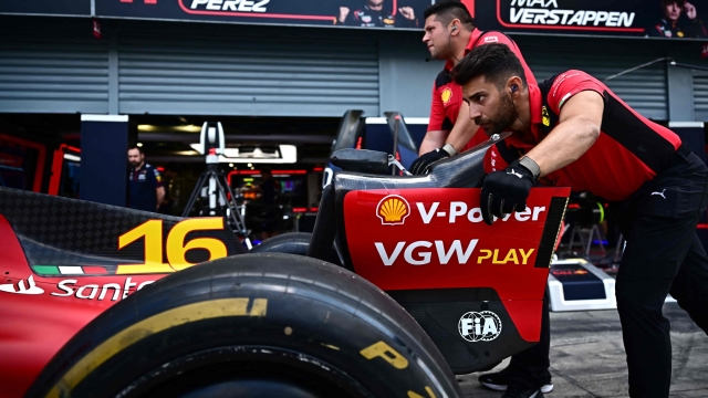 Ferari mechanics push the  the vehicle of Ferrari's Monegasque driver Charles Leclerc past the boxes of Red Bull Racing's Mexican driver Sergio Perez and Red Bull Racing's Dutch driver Max Verstappen at the paddock of the Monza Circuit ahead of the Italy's Formula One Grand Prix, in Monza northern Italy, on August 31,  2023. The 2023 Italy's Grand Prix will take place on September 3, 2023. (Photo by Marco BERTORELLO / AFP)