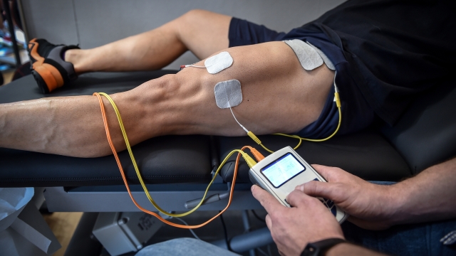 Muscle stimulator device with electrodes applied to quadriceps by a professional physiotherapist