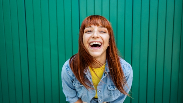 Young beautiful caucasian red hair woman laughing at the camera - Portrait green background