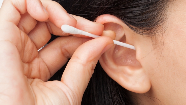 Woman cleaning ear using cotton stick