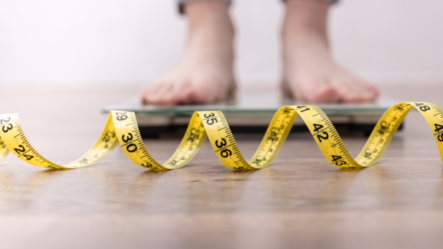 Women's legs on the scales, close-up of a measuring tape, the concept of losing weight, healthy lifestyle.