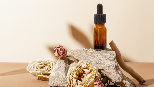 Glass bottle for cosmetic product and dried roses on stone and beige background. High quality photo