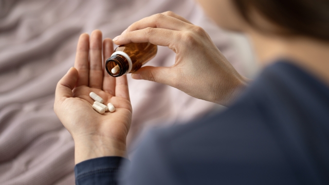 Closeup of woman hand pouring capsules from a pill bottle into hand