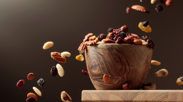 Flying dried fruits and nuts. The mix of nuts and dried berries are in a wooden bowl.