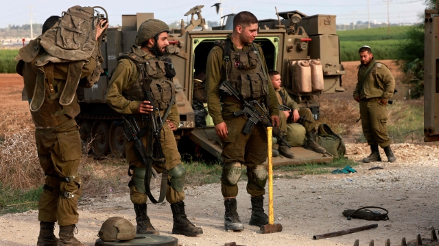 Israeli troops gather  at an undisclosed location on the border with the Gaza Strip on October 8, 2023. Israel's prime minister of October 8 warned of a "long and difficult" war, as fighting with Hamas left hundreds killed on both sides after a surprise attack on Israel by the Palestinian militant group. (Photo by Menahem KAHANA / AFP)
