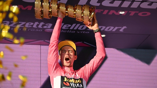 TOPSHOT - Jumbo-Visma's Slovenian rider Primoz Roglic celebrates on the podium with the race's winner's "Trofeo Senza Fine" (Endless Trophy) after winning the Giro d'Italia 2023 cycling race in Rome on May 28, 2023. (Photo by Alberto PIZZOLI / AFP)