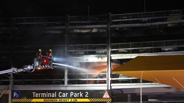 Firemen battle a fire at London's Luton Airport which caused a partial collapse of a parking structure in Luton on October 11, 2023. Five people, including four firefighters and an airport employee, were admitted to hospital, according to the local ambulance service. (Photo by HENRY NICHOLLS / AFP)