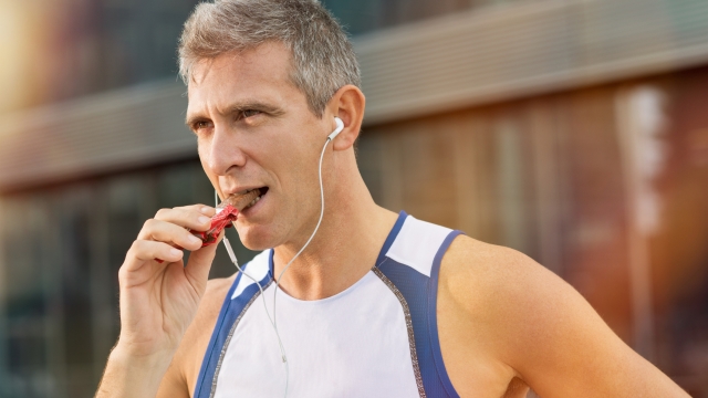 Portrait Of Fitness Mature Man Eating A Energy Bar Of Chocolate