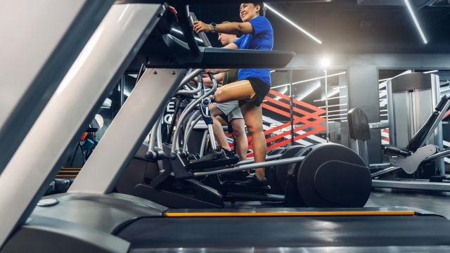 Sports woman with artificial leg running on treadmill at gym. Woman with prosthetic leg using walking on treadmill while working out in gym.