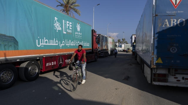 NORTH SINAI, EGYPT - OCTOBER 16: A person cycles past aid convoy trucks loaded with supplies on October 16, 2023 in North Sinai, Egypt. The aid convoy, organized by a group of Egyptian NGOs, set off today from Cairo for the Gaza-Egypt border crossing at Rafah. On October 7th, the Palestinian militant group Hamas launched a surprise attack on border communities in southern Israel, spurring the most violent flare-up of the Israel-Palestine conflict in decades. Israel launched a vast bombing campaign in retaliation and has warned of an imminent ground invasion. (Photo by Mahmoud Khaled/Getty Images)