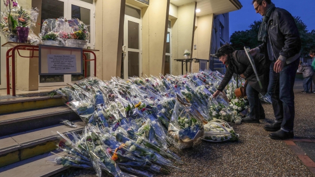 People pay their tribute beside flowers layed outside the Gambetta high school for French teacher Dominique Bernard who died in a knife attack on October 13, in Arras, north of France on October 16, 2023. (Photo by Denis Charlet / AFP)
