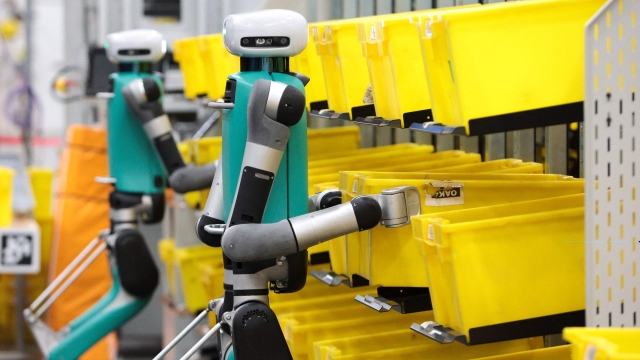 TOPSHOT - Bipedal robots in testing phase move containers during a mobile-manipulation demonstration at Amazon's "Delivering the Future" event at the company's BFI1 Fulfillment Center, Robotics Research and Development Hub in Sumner, Washington on October 18, 2023. (Photo by Jason Redmond / AFP)