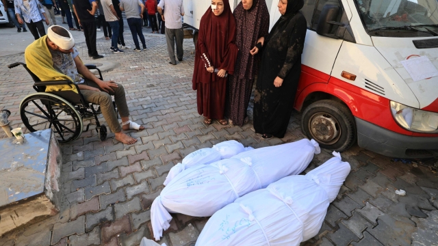 Women stand next to the bodies wrapped in shrouds of family members killed during an Israeli military strike as they are taken for burial from the Al-Aqsa hospital in the town of Deir Al-Balah, in the central Gaza Strip, on October 15, 2023. Israeli forces were on October 15, readying for a looming Gaza ground invasion aimed at destroying Hamas, the Palestinian Islamist militant group that unleashed the bloodiest attack in the country's history. (Photo by Mahmud HAMS / AFP)