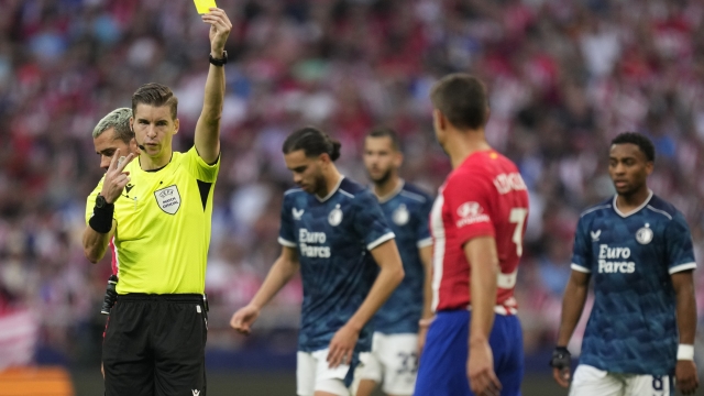 French referee Francois Letexier shows the yellow card to Atletico Madrid's Cesar Azpilicueta during the Champions League Group E soccer match between Atletico Madrid and Feyenoord at the Metropolitano stadium in Madrid, Spain, Wednesday, Oct. 4, 2023. (AP Photo/Bernat Armangue)