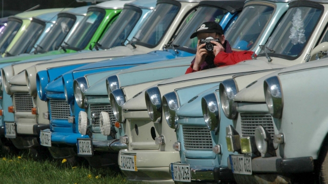 epa000428296 A visitor takes pictures of the Trabant cars lined up at the 11th International Trabi meeting at the airport of Anklam, Germany, Saturday 07 May 2005. More than 580 of the legendary cars with the plastic body and thousands of visitors have come to the first of 50 nationwide meetings of Trabi lovers this year.  EPA/STEFAN SAUER