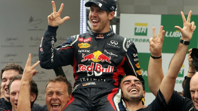 German Formula One driver Sebastian Vettel (C) celebrates his F-1 World Championship with Red Bull teammates after arriving 6th in the Brazil F-1 GP on November 25, 2012 at the Interlagos racetrack in Sao Paulo, Brazil.    TOPSHOTS/AFP PHOTO/ORLANDO KISSNER