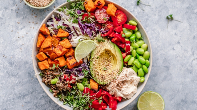 Overhead view of a colourful vegan bowl with quinoa, sweet potato, avocado, hummus and variety of veggies