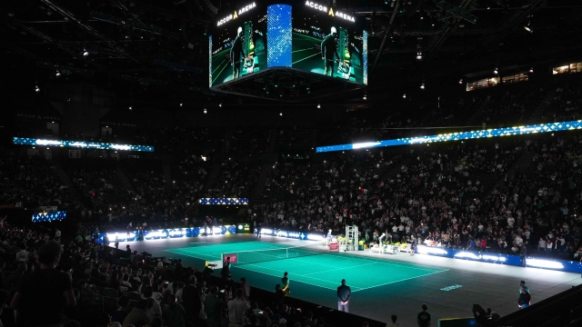 Italy's Jannik Sinner (R) and US' Mackenzie Mcdonald arrive on the illuminated court prior to their men's singles match on day three of the Paris ATP Masters 1000 tennis tournament at the Accor Arena - Palais Omnisports de Paris-Bercy - in Paris on November 1, 2023. (Photo by Dimitar DILKOFF / AFP)