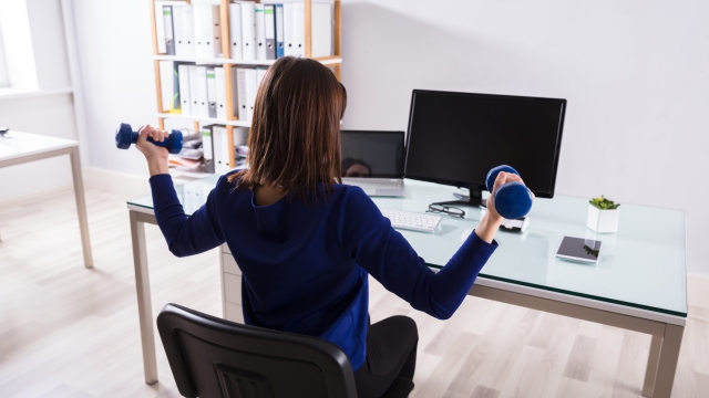 Young Businesswoman Sitting On Chair Doing Workout With Dumbbell