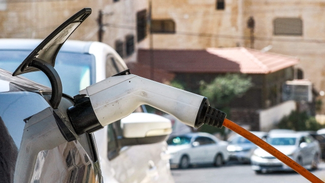 This picture taken on September 21, 2023 shows an electric vehicle plugged into a power inlet for charging in Amman. Electric car sales are surging in Jordan, a trend drivers and showrooms attribute to high petrol prices more than any concerns about air pollution and climate change. Boosted by low import taxes, especially affordable Chinese-made EV models have become a common sight on the streets of Amman and the kingdom's desert highways. (Photo by Khalil MAZRAAWI / AFP)