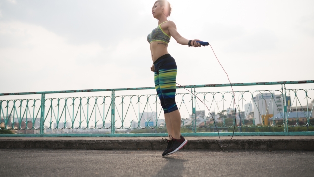 Slim young Asian woman exercising with skipping rope