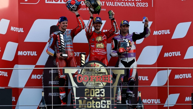 Ducati Italian rider Francesco Bagnaia (C) celebrates on the podium with second-placed Ducati Italian rider Fabio Di Giannantonio (L) andd third-placed Ducati French rider Johann Zarco after winning the MotoGP Valencia Grand Prix at the Ricardo Tormo racetrack in Cheste, on November 26, 2023. Italy's Francesco Bagnaia enjoyed a dream day as he retained his MotoGP world title and crowned it with victory in the final race of the season in Valencia today. The 26-year-old Ducati rider had been assured of the championship when his sole rival Jorge Martin crashed early in the race. (Photo by JOSE JORDAN / AFP)