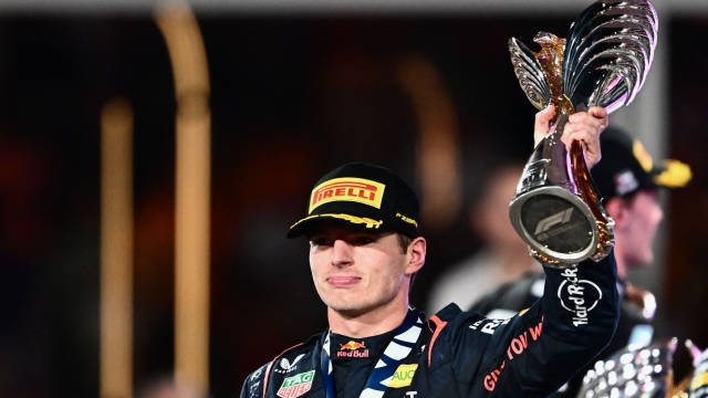 TOPSHOT - Red Bull Racing's Dutch driver Max Verstappen celebrates with the trophy on the podium after winning the Abu Dhabi Formula One Grand Prix at the Yas Marina Circuit in the Emirati city on November 26, 2023. (Photo by Jewel SAMAD / AFP)