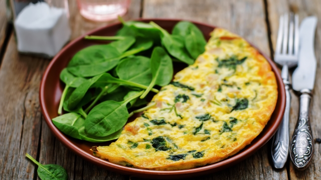 Frittata with chicken and spinach and fresh spinach on a dark wood background. tinting. selective focus