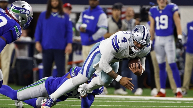 Dallas Cowboys quarterback Dak Prescott (4) is stopped after a short run by Seattle Seahawks safety Julian Love, left rear, in the first half of an NFL football game in Arlington, Texas, Thursday, Nov. 30, 2023. (AP Photo/Roger Steinman)