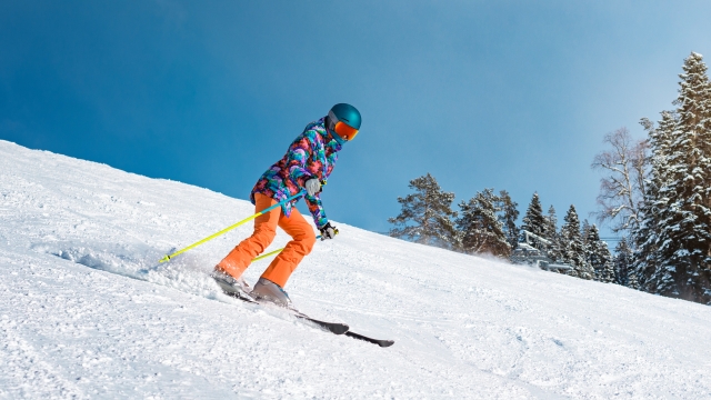 Female skier goes down the slope on a sunny day at a mountain resort.