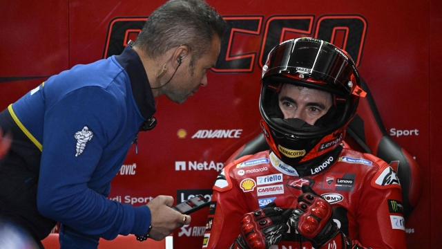 Ducati Italian rider Francesco Bagnaia speaks with a Michelin mechanic during the second free practice session of the MotoGP Valencia Grand Prix at the Ricardo Tormo racetrack in Cheste, on November 25, 2023. (Photo by JAVIER SORIANO / AFP)