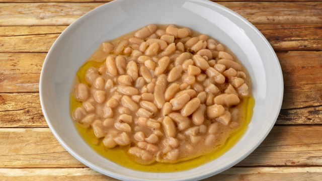 Bean soup seasoned with extra virgin olive oil in a white dish on rustic wooden boards. Clipping path included
